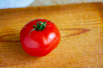 Bright red ripe tomato on a wooden board on the table