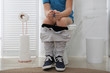 Boy suffering from hemorrhoid on toilet bowl in rest room, closeup