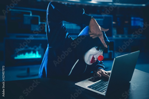 Fotomural Hacker wearing clown mask using a laptop