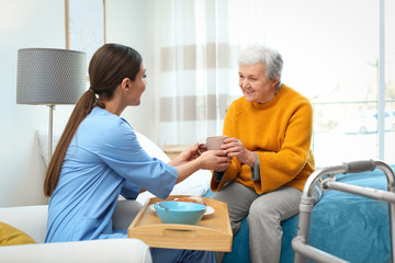 Canvas Print - Care worker serving dinner for elderly woman in geriatric hospice