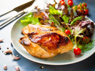 Wall Mural - Grilled chicken breast steak served with fresh cherry tomato and salad on a grey color dish.