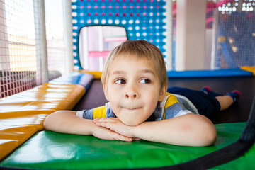 Wall Mural - Little boy resting on trampoline in play centre