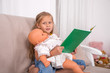 © rozaivn58 - Shot of a little girl sitting on the sofa   and plaing with her doll