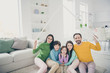 © deagreez - Portrait of nice attractive perfect cheerful family three pre-teen kids mom dad sitting on carpet floor holding in hand roof over head good change at light white interior style house living-room