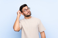 Young Handsome Man With Beard Over Isolated Blue Background Having Doubts And With Confuse Face Expression