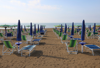 Wall Mural - many closed blue sun umbrellas on the beach