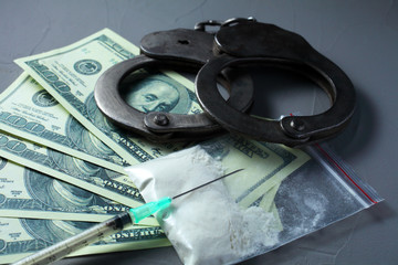 concept of criminal liability for possession and use of narcotic substances. Handcuffs, white powder bag, syringe.