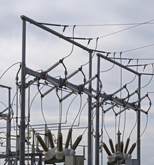 Close-up sectional view of parts of the structure and elements of a substation for electricity distribution under a grey winter sky