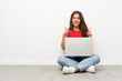 © luismolinero - Young woman with a laptop sitting on the floor pointing with the index finger a great idea