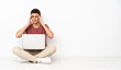 © luismolinero - Teenager man sitting on the flor with his laptop with headache