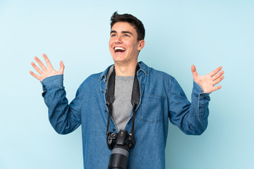 Wall Mural - Teenager photographer man isolated on blue background with surprise facial expression