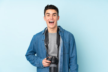 Wall Mural - Teenager photographer man isolated on blue background with surprise facial expression