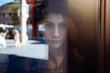 © Westend61 - Portrait of young woman behind window pane