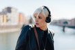 © Westend61 - Italy, Verona, portrait of blond woman listening music with headphones