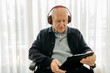 © Westend61 - Senior man sitting in wheelchair reading using digital tablet while listening music with headphones