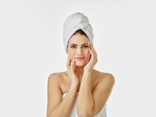 Portrait Of Smiling Woman With Hairs Wrapped In Towel Against White Background