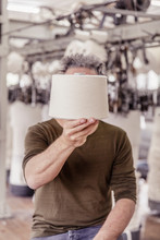Man Holding A Cotton Reel In Front Of His Face In A Textile Factory