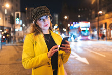 Woman With Her Smartphone In The City At Night Next To A Road