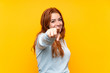 © luismolinero - Teenager redhead girl over isolated yellow background points finger at you with a confident expression