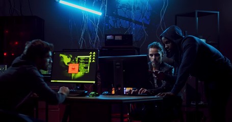 Mixed-races young hackers, two men and woman hacking the programs and stealing data from database, the being afraid and running away because can be caught.