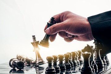 Wall Mural - hand of businessman moving chess figure in competition success play. strategy, management or leadership and business success or victory concept