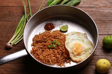 Wall Mural - Mi goreng or mee goreng mamak, Indonesian and Malaysian cuisine, spicy fried noodles on wooden table.