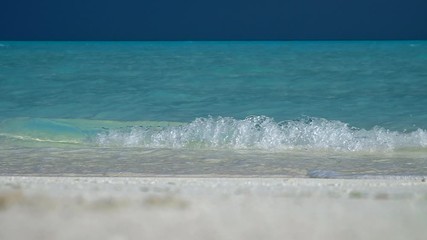 Wall Mural - Blue sea wave breaks on the sandy beach in Maldives