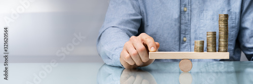 Fotografía Businessman Balancing Coins On Wooden Seesaw