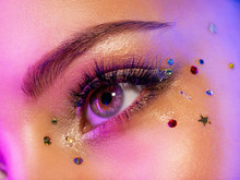 Colorful Makeup. Bright And Intense Makeup. Female Eye Close-up With Bright Makeup. Fashionable Stylish Makeup With The Use Of Sequins. Stylish Image. The Face Is Illuminated By Bright Lights.