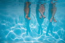 Close Up Of Friends, Family Legs Underwater In The Swimming Pool With Copy Space