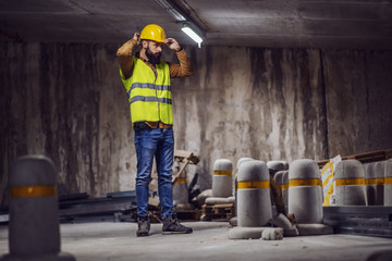 Wall Mural - Full length of handsome caucasian worker putting his helmet on while standing in tunnel in construction process.