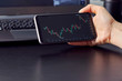 © yavdat - Female hand with smartphone trading stock online. Business concept. trading online on smartphone with business woman hand