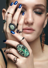 Wall Mural - Young woman with eyes closed and many bijouterie rings with stones on fingers