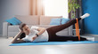Young woman strengthening hips lying on side and lifting one leg using resistance band tracking time