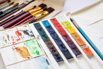  Paint brushes and watercolor paints, tempera paints on the table in a workshop, selective focus, close up