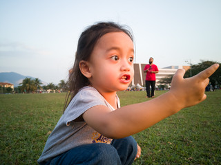 Asian  toddler sit on the grass in the park.