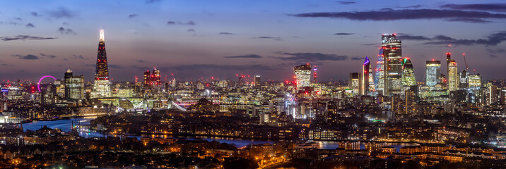 Fototapete - Panorama der modrnen Skyline von London, Großbritannien, am Abend mit den beleuchteten Hochhäusern an der Themse und zahlreichen Sehenswürdigkeiten