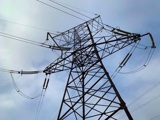 High voltage electric tower against the blue sky. High steel power transmission pole in production.