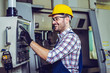 © zorandim75 - Industry Worker entering data in CNC machine at factory.