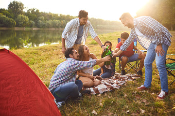 Wall Mural - Young people drink, eat and clink glasses at a picnic