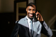© Carlos David - Close up portrait of a happy smiling young man in business suit holding cell phone, talking and looking at camera