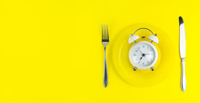 Alarm Clock With Fork And Knife On The Table. Time To Eat, Breakfast, Lunch Time And Dinner Concept