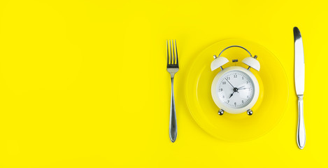 Alarm clock with fork and knife on the table. Time to eat, Breakfast, Lunch Time and Dinner concept