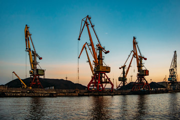  Harbor cargo cranes on sunset sky background