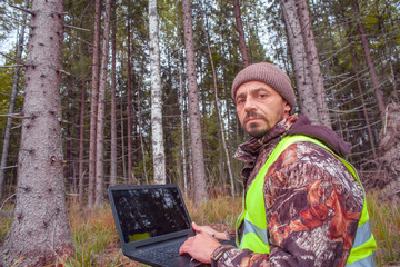 Wall Mural - Ecologist with a computer. Forest engineer oversees the development of the forest. Ecologist with a computer. The forester is watching the development of the forest. Forestry and afforestation.