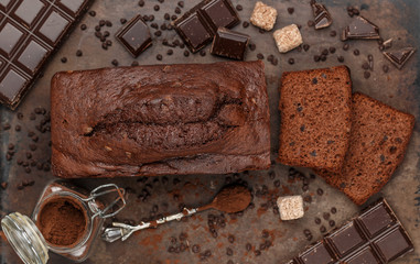 Wall Mural - Sliced homemade chocolate banana pound cake loaf. Delicious dessert. The ingredients and the pie on the baking sheet. Selective focus, top view