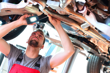 Auto mechanic repairs vehicle in a workshop - checking brakes for safety