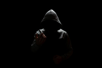 an unknown person in a hood lures into the darkness