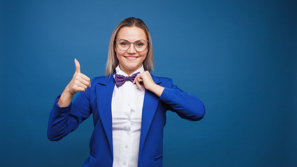 Wall Mural - Funny business lady in a blue jacket and purple bow tie. jumps for joy and gives a thumbs up.