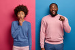 © wayhome.studio  - Speechless Afro American woman gasps from fear, happy bearded man points directly at camera, express shock and happiness, dressed in casual bright clothes, pose against two colored background